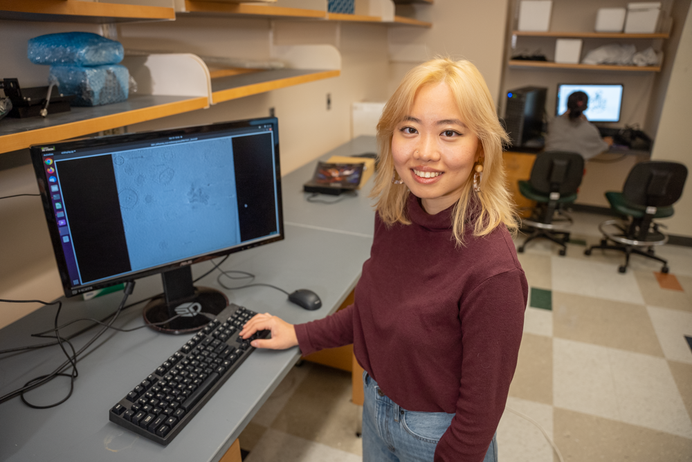 portrait of Judy Huang next to a computer.