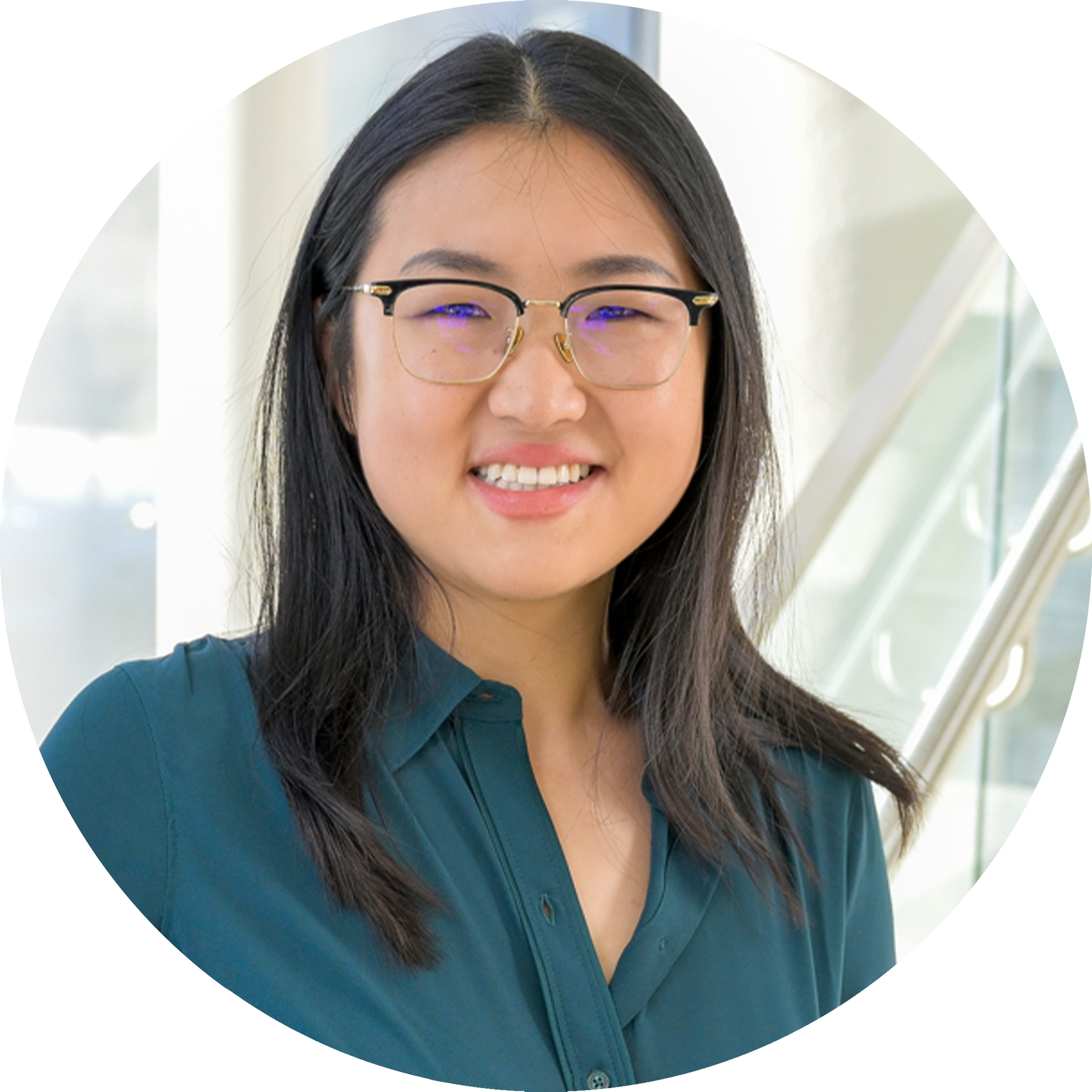 A headshot of Qinglan Ling, wearing glasses and a smile. She is wearing a teal blouse in a pose in front of a large window in the background.