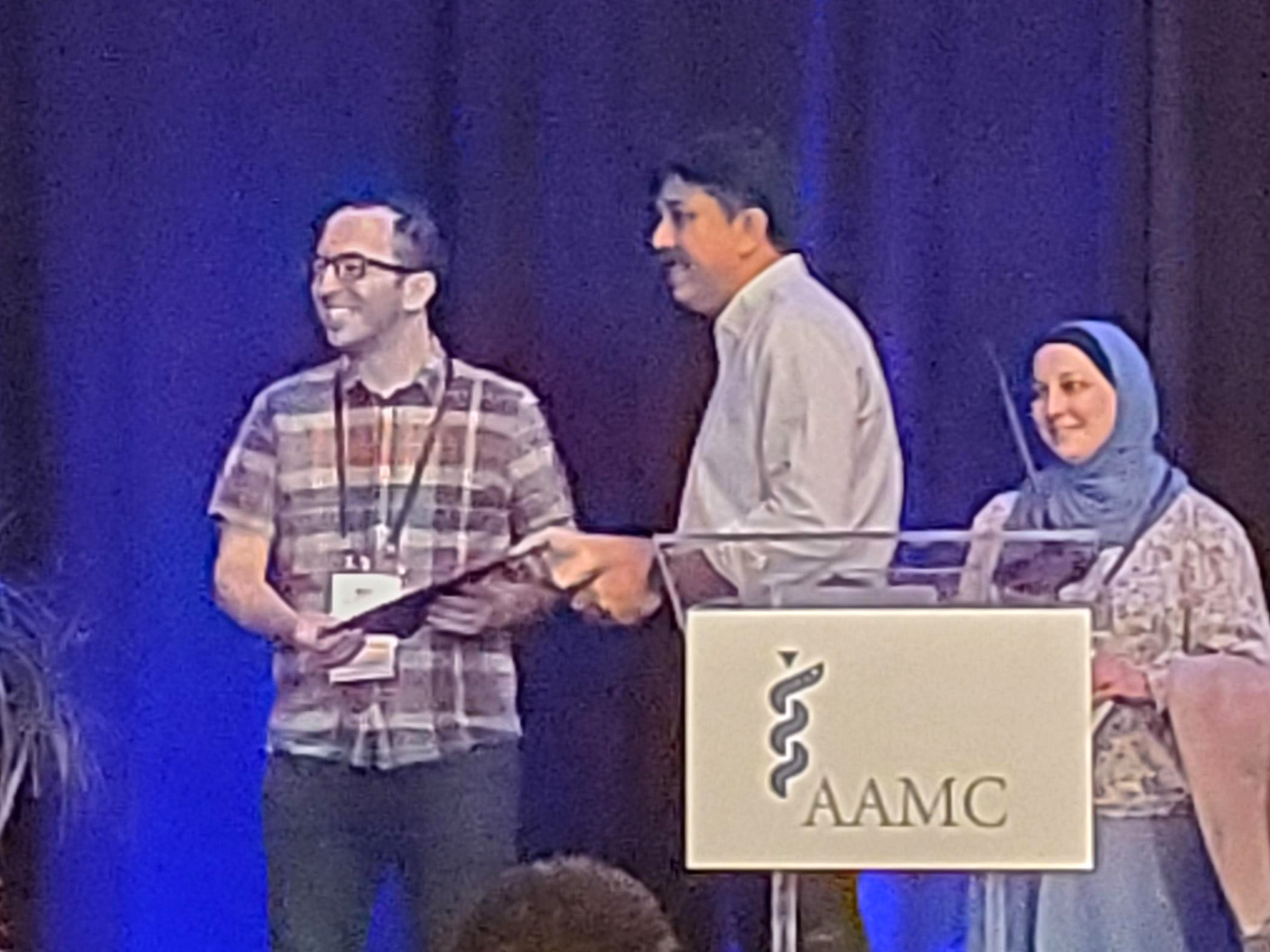 iCAP staff receiving certificate at AAMC 2023. In the shot are two others.