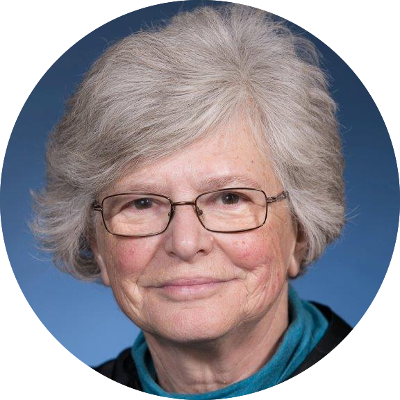 Circular portrait of Dr. Catarina Kiefe, who has short white hair and glasses and is wearing a teal turtleneck and smiling