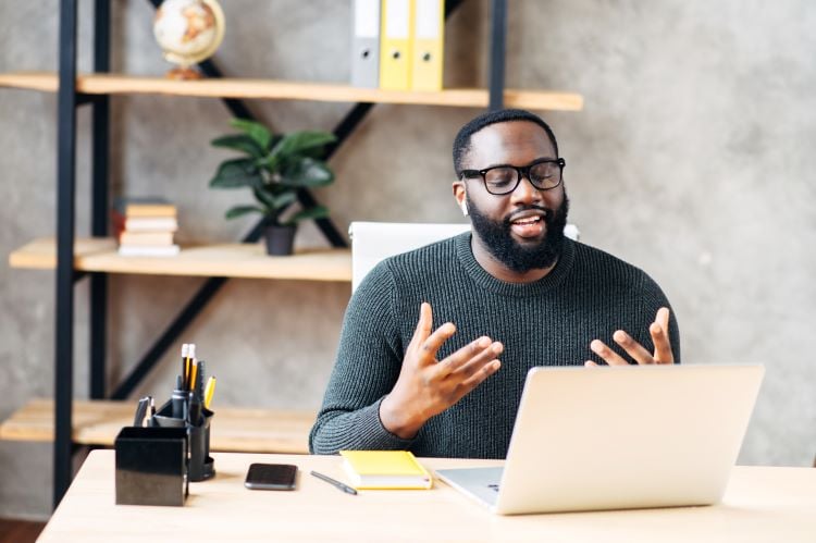 black man leading a virtual meeting on a laptop from his home office