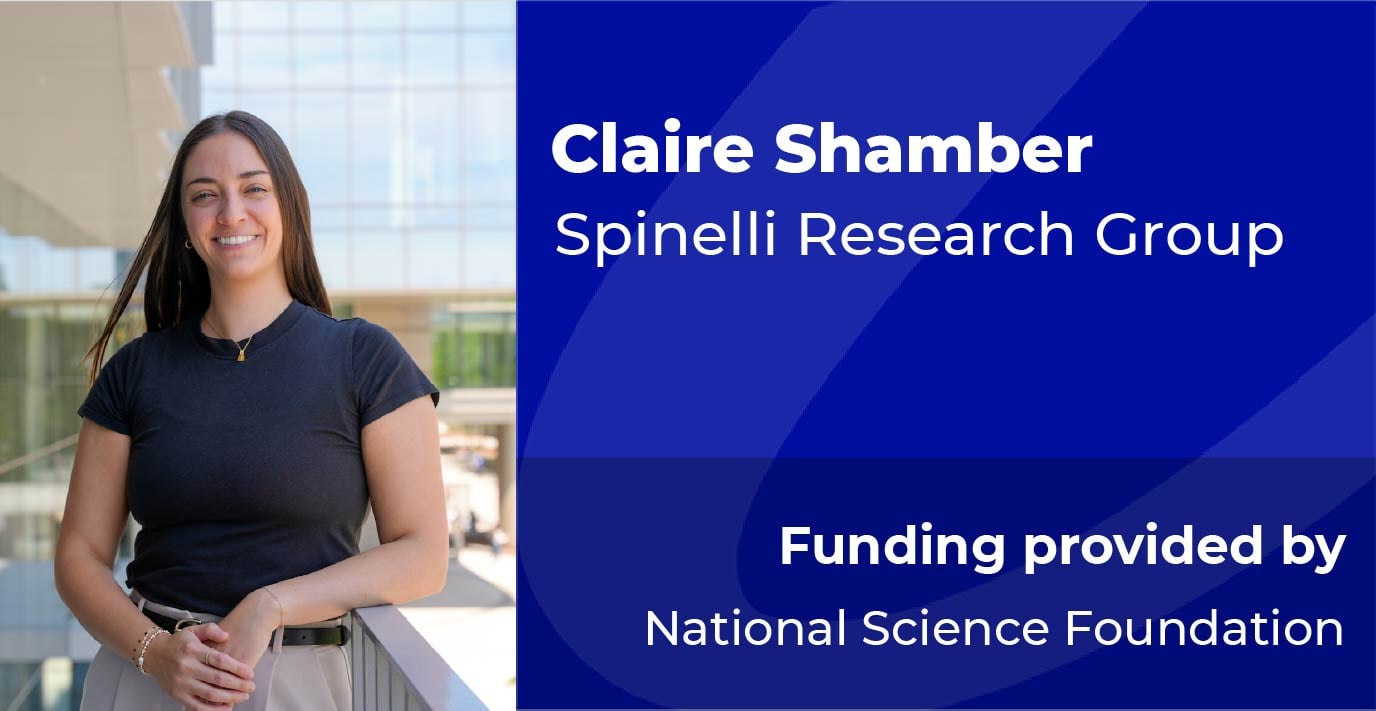 A researcher stands beside a blue information panel displaying the text: “Claire Shamber, Spinelli Research Group. Funding provided by National Science Foundation.”