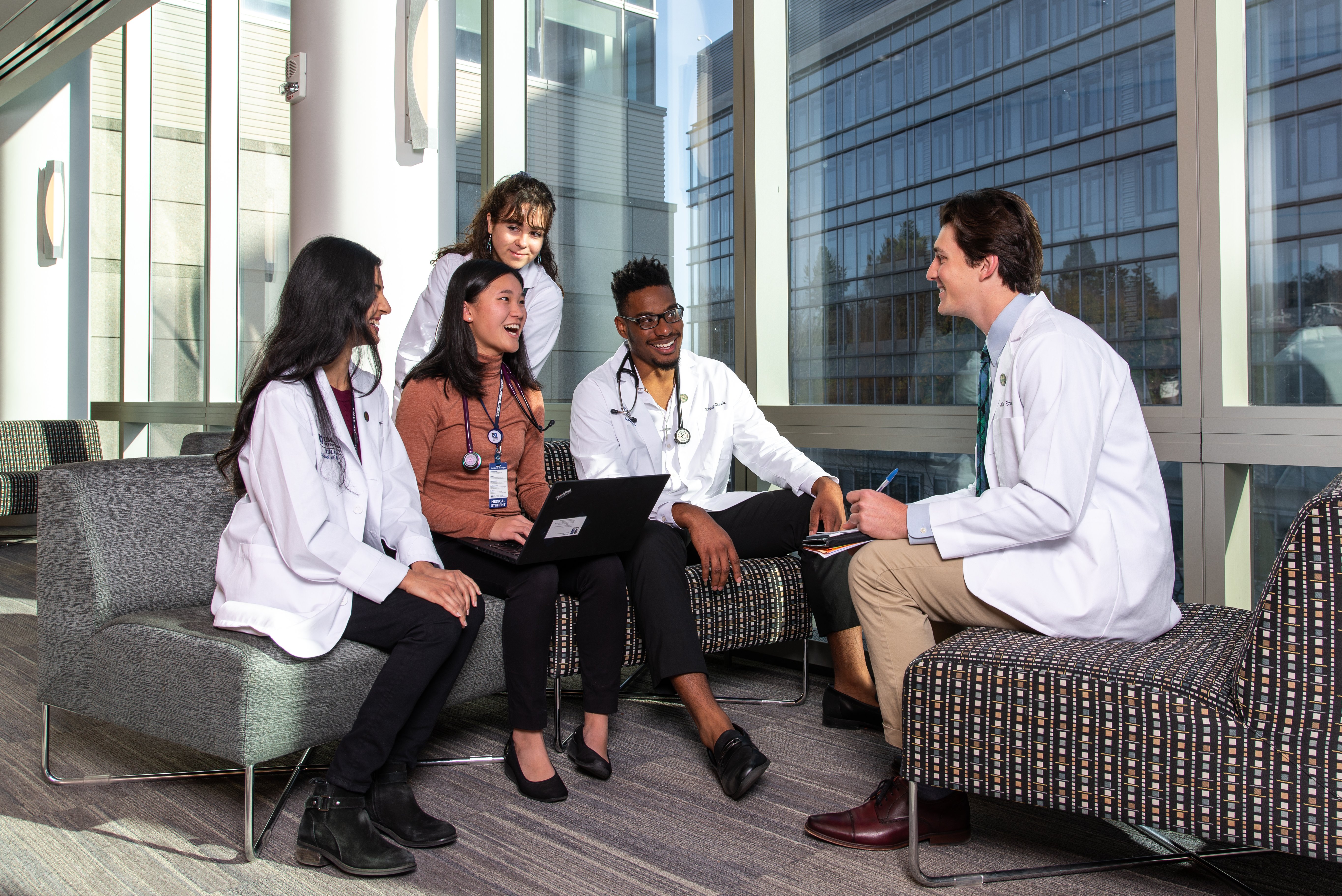 Medical students in white coats gathered together and conversing.