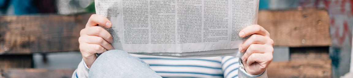 a person sitting on a bench reading a newspaper