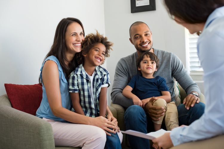 multi ethinic family white mom black dad and biracial sons sitting in a therapist office
