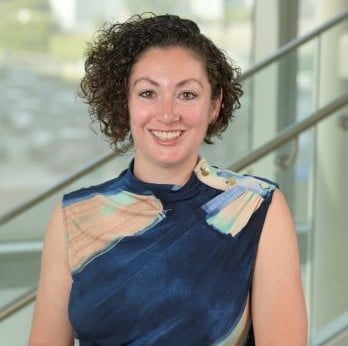 white woman with short dark curly hair smiling