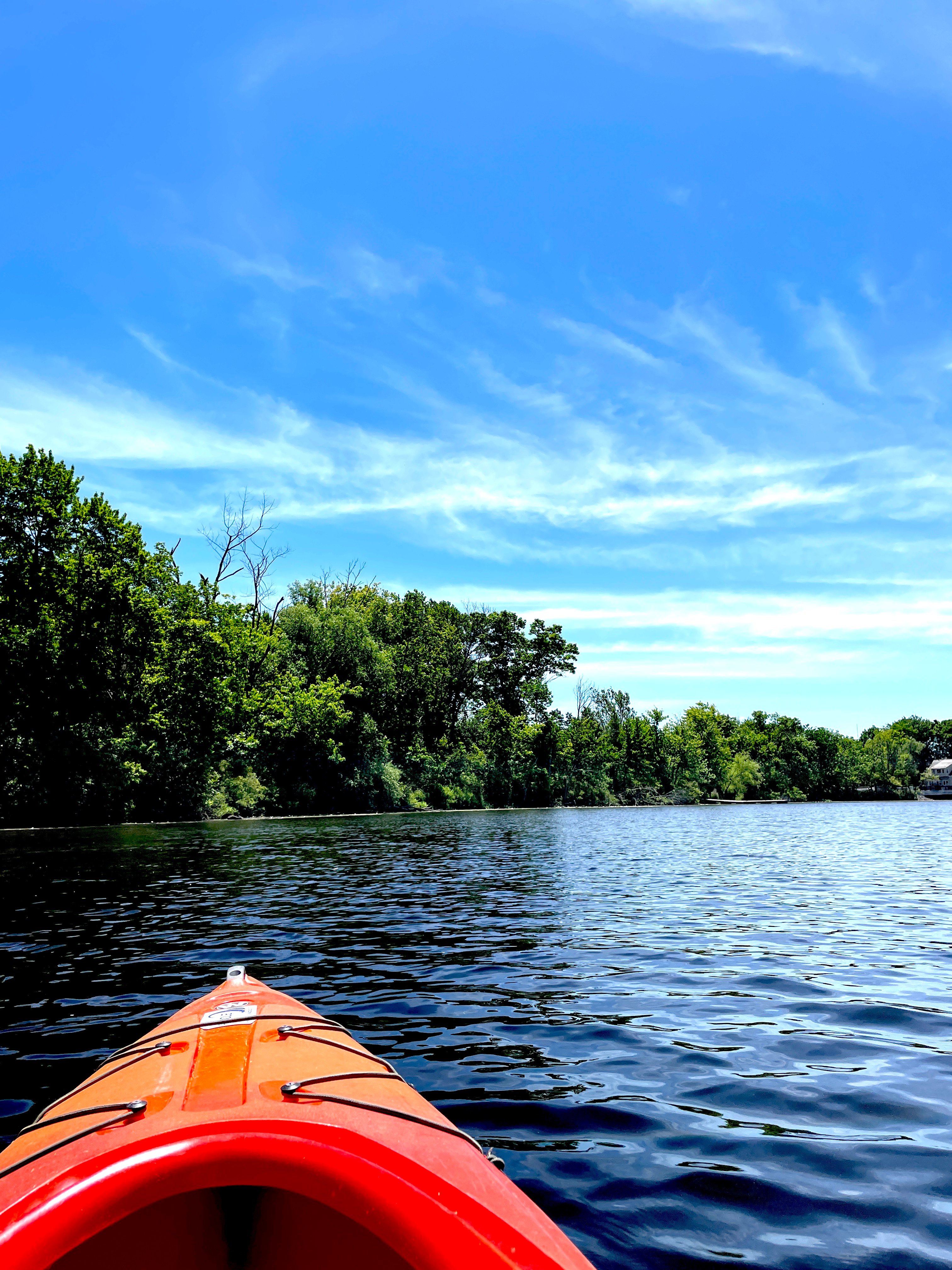 red kayak on calm water with lots of trees around the water