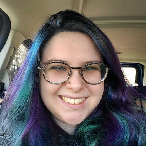 white woman with purple & blue hair and glasses