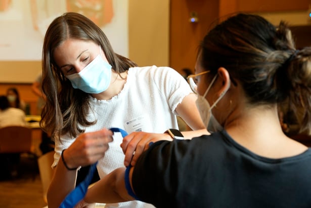 Sara Buscher (left) puts a tourniquet on fellow first-year medical student Minhtam Tran during the Stop the Bleed exercise.