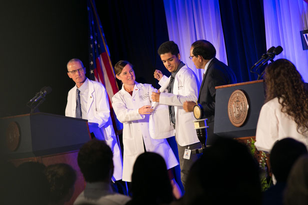 Cynthia A. Ennis, DO, helps Timothy Arjun Baloda with his new white coat.