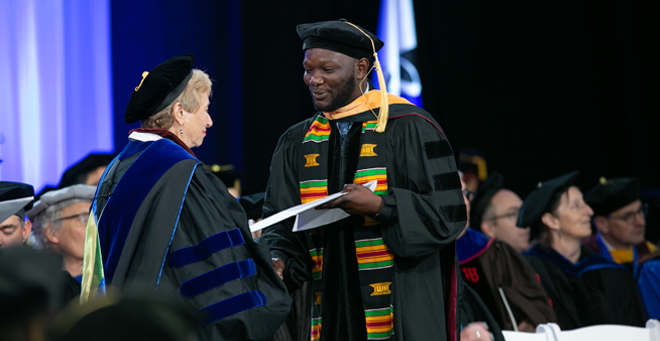 Badu Adjei accepts his Doctor of Nursing Practice degree