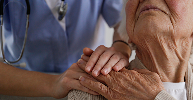 Older adult holding the hand of a health care worker