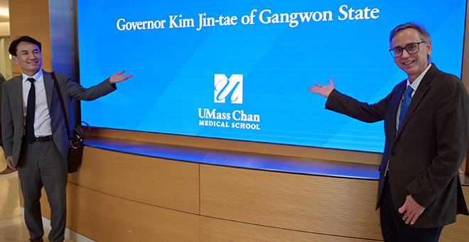 Kim Jin-Tae and Jeroan Allison standing in front of a digital sign