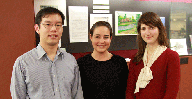 Third-year medical students Mark Fusunyan, Courtney Temple and Alyse Wheelock, pictured in front of an exhibit at the Lamar Soutter Library that showcases original artwork along with story excerpts from When We Were Home. 