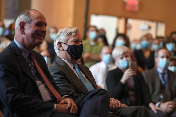 Chancellor Michael F. Collins and President Meehan listen to remarks from Gerald Chan.