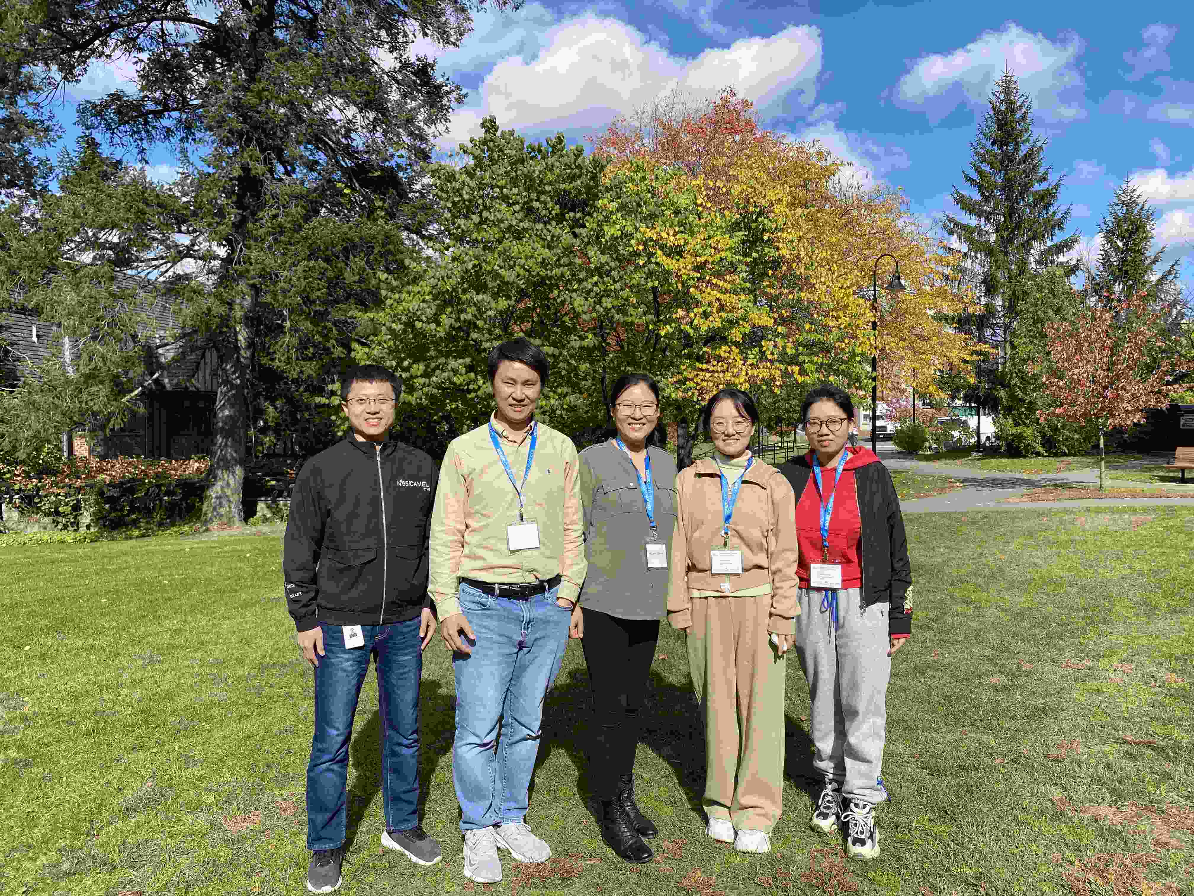 Five people standing in front of some trees, smiling for a group photo.