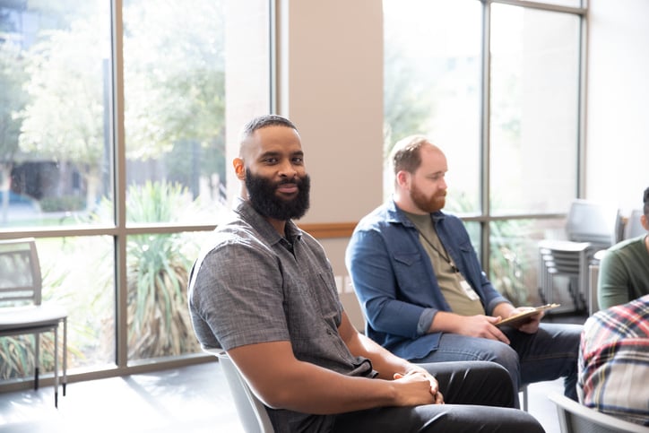 During the group therapy meeting, an adult man smiles for a photo.
